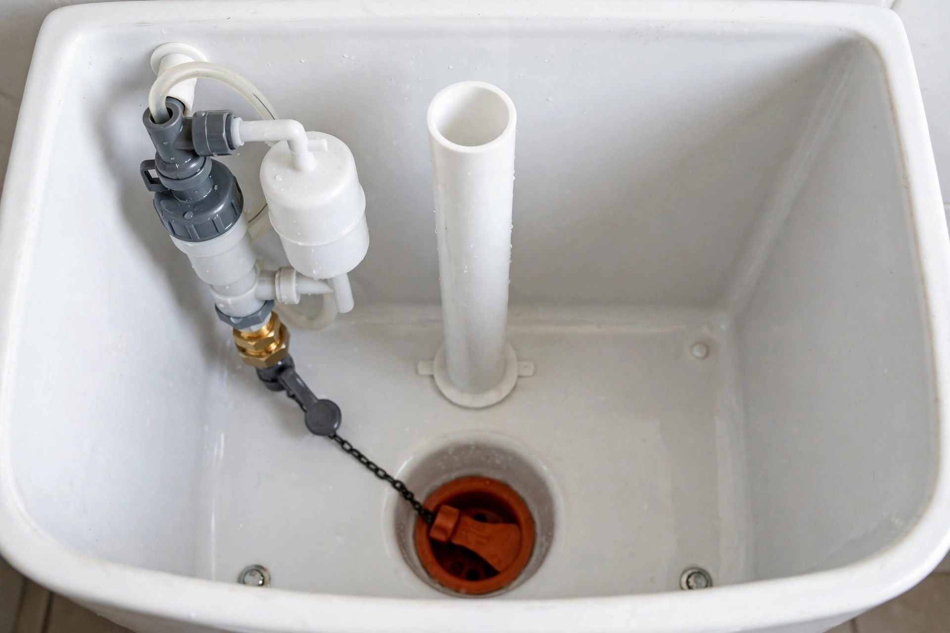 Inside a toilet tank showing the fill valve, flapper, float and overflow tube — fixing a running toilet in Arcadia